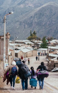 PINCHOLLLLO, COLCA VALLEY, PERU - 20 HAZİRAN 2018: Perulu bir aile, arka planda dağ olan Pinchollo, Colca Valley, Peru 'daki küçük bir köyde çantalarıyla caddenin karşısına yürür