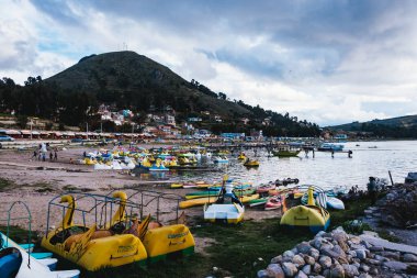 COPACABANA, BOLIVIA - 15 Ocak 2018: Copacabana 'nın Titicaca Gölü kıyısındaki manzarası, renkli ayak pedallı botlar ve arka planda yeşil bir dağ