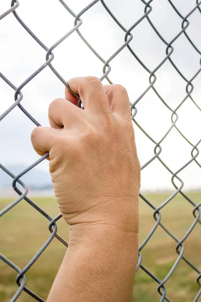 Zincir bağlantı çit üzerinde tutan el — Stok fotoğraf