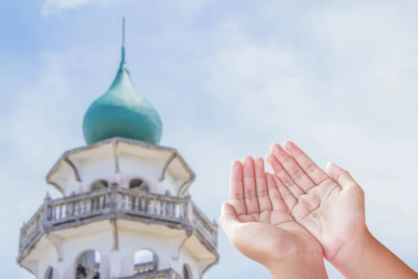Люди открывают пустые руки с ладонями вверх над размытой мечетью — стоковое фото