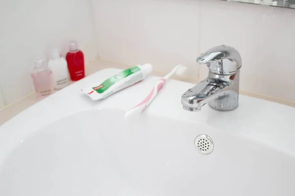Torneira, pasta de dentes, escova de dentes e acessórios de banho — Fotografia de Stock