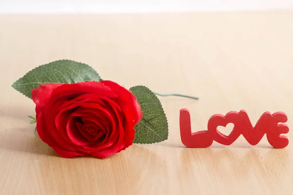 Γράμματα "αγάπη" και κόκκινο τριαντάφυλλο στο ξύλινο τραπέζι — Φωτογραφία Αρχείου