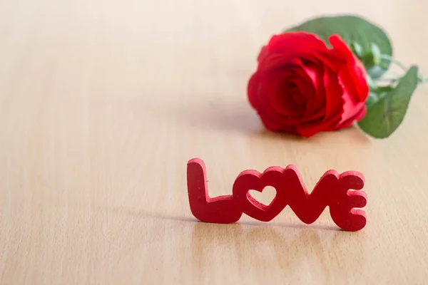 Letters "liefde" en rode roos op houten tafel — Stockfoto