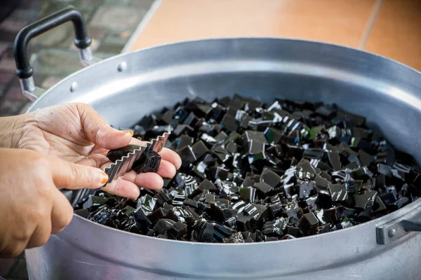 hand of seller cutting grass jelly