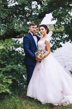 Nehir kıyısında bir ağacın altında üzerinde gelin sarılma damat