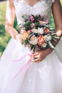 Güneşli bir günde, beyaz bir elbise içinde elinde tutan bir güzel düğün buketi Gelin