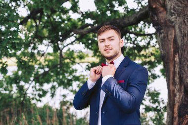 Damat düğün günü doğada ayakta ve papyon için dayanıyoruz