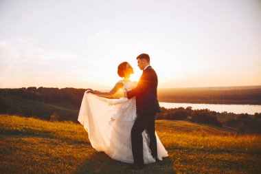 Doğa günbatımı sırasında gelin ve damat kucaklama