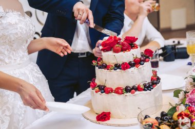 Gelin ve damat taze çilek ile süslenmiş büyük bir düğün pastası kesti