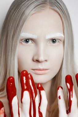 Bir kız korkmuş göz ve ellerini kanıyla düz görünüyor. Beyaz kaş ve kirpik