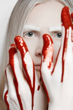 Sarışın kız parmaklarını arıyor. Elleri kan içinde. Makyaj. Beyaz kaş ve kirpik.