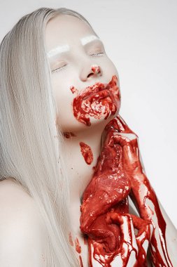 Kız, Sarışın, büyük bir parça et, kanlar içinde vücudun karşı eğilir.