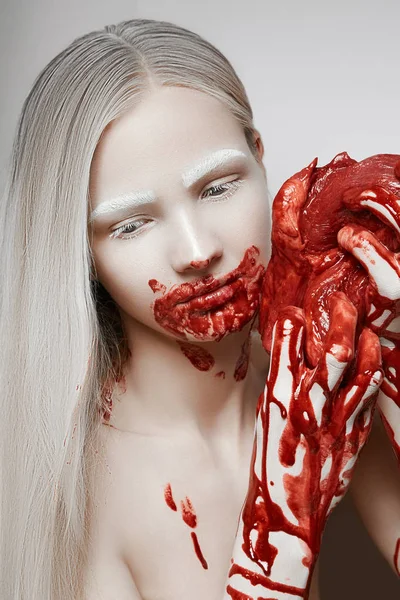 Genç bir kız, Sarışın, taze et, onun elinde tutan tüm kan lekeli.