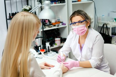 Donanım manikür güzellik salonu içinde. Gözlük ve pembe maske manikürcü manikür çivi tatbikat parmaklar üzerinde geçerlidir..