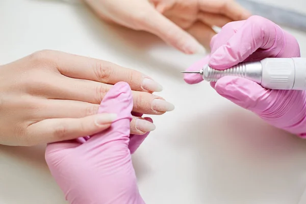 Master of manicure polishes the nails of a girl in a beauty salon