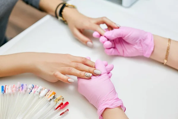 A manicurist examines the nails of a client after work