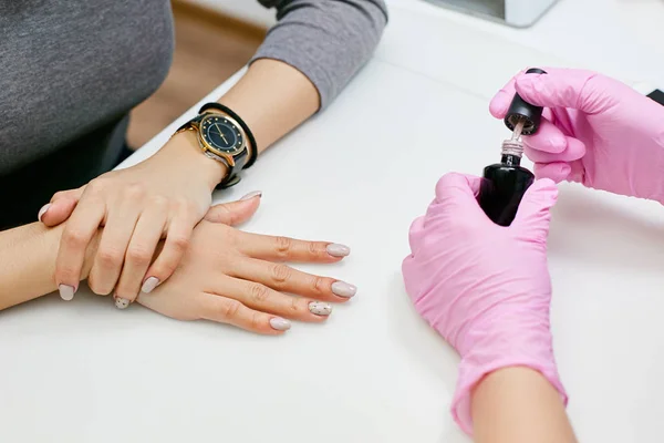 Master of manicure puts a nail polish on the girl\'s nails