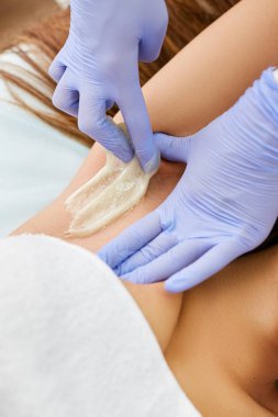 Güzellik salonunda sugaring ustası saç kapalı kız koltukaltı alır.
