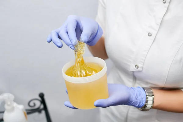 The master of sugaring in a beauty salon prepares a paste for drawing