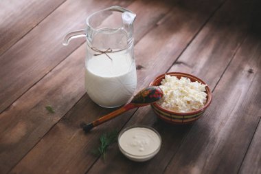 Doğal ahşap bir sürahi taze süt, peynir ve ekşi krema bir tablo ile