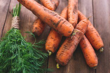 Taze havuç ve bir demet dereotu ahşap bir masaya. Sağlıklı beslenme