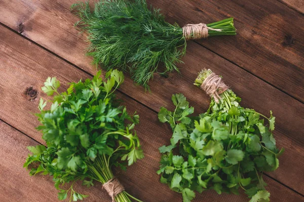 Bundles of dill and parsley on a wooden table