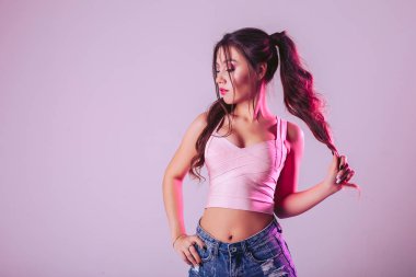 Studio bir ışık mor zemin üzerine güzel bir kadın. Saçını başını yana çevirerek elinizle tutun