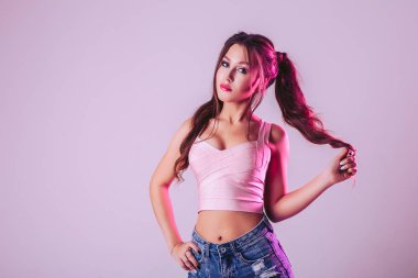 Studio bir ışık mor zemin üzerine güzel bir kadın. Saçına elini tutun ve düz bak