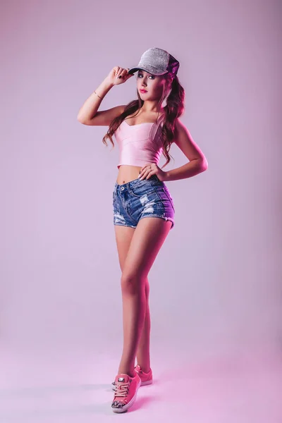 スタジオで薄紫色の背景でポーズ キャップでセクシーな女の子 — ストック写真