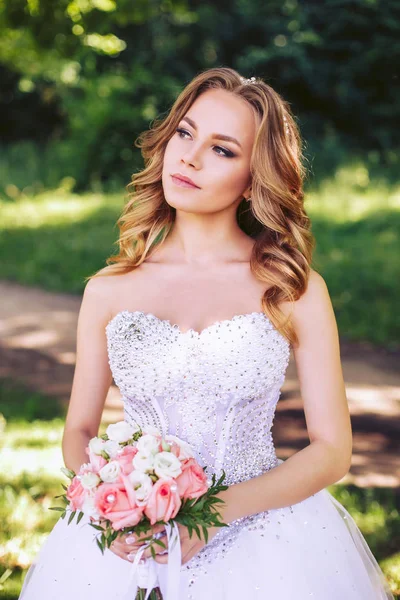 Gelin düğün buket onun elinde tutuyor. Doğada Genç gelin