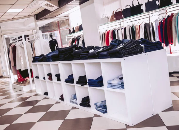 Interior of a clothing store in a shopping center. Shelves with jeans and showcases with women\'s clothing.