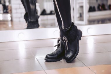 Siyah hakiki deri kürk bir Ayakkabı mağazası ile yeni kışlık botlar kız seçer.