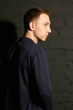 Mavi bir ceket ve yan duran bir gri tuğla duvara bir genç adam