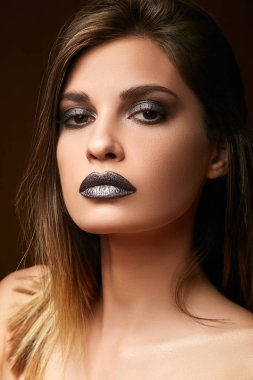 Parlak koyu makyaj ve akan saç ile görkemli genç esmer.
