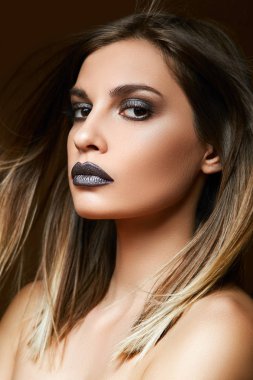 Genç bir esmer anlamlı gözleri ve yüzünde koyu makyaj portresi.