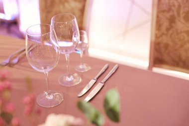 Ziyafet salonu tabloda şarap bardakları ve gümüş çatal bıçak takımı ile servis edilir.