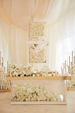 Lüks masa yeni evliler ile lots-in beyaz çiçekler ve mumlarla süslenmiş. Düğün çadırda. Gelin ve damat, cam masa.