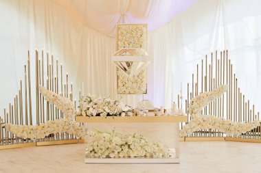 Düğün masa yeni evliler çadırda. Arka plan üzerinde beyaz kumaş. Işıkları ile şık metal çelenk