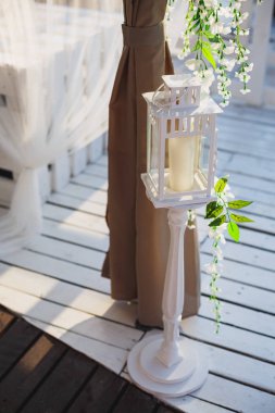 Bir mum bir ahşap zemin üzerinde uzun boylu beyaz şamdanla