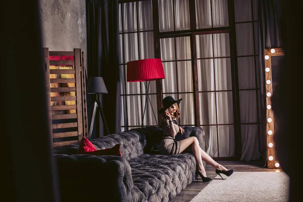 高のステンド グラスの窓と豪華なインテリアで高価なソファに座っている黒帽子でスタイリッシュな女の子 — ストック写真
