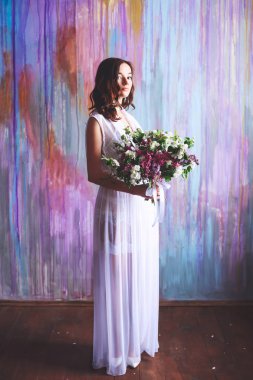 Büyük bir buket çiçek çok renkli bir arka plan üzerinde sabahın erken saatlerinde ile borough elbiseli genç gelin