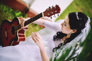 Beyaz elbiseli genç gelin bir müzik aleti elinde taşır.