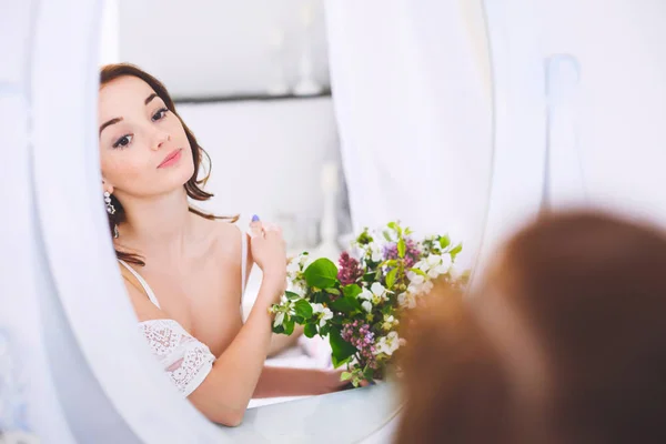 The bride looks in the mirror before the triumph