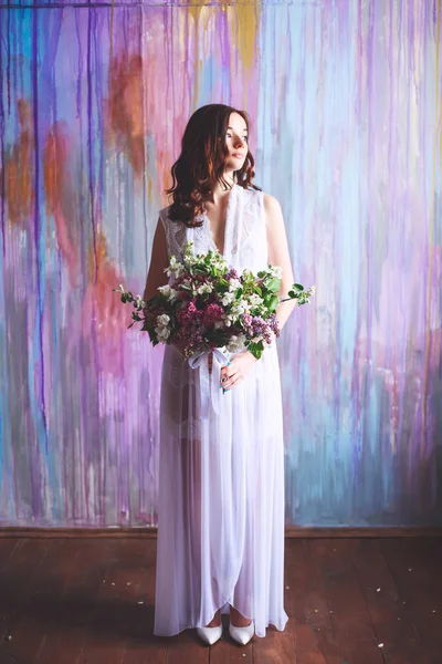 Young bride in a borough dress with a large bouquet of flowers in the early morning