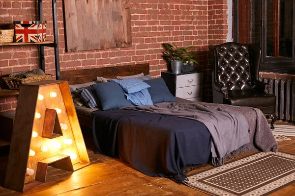 Moderní ložnice s dřevěnou postelí v tmavých barvách, stěny vyzdobené cihlovým zdiva — Stock fotografie