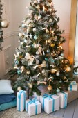 Luxusní vánoční stromeček v obytné budově zařízené s mnoha hračkami a koule. Dárky pod stromeček.
