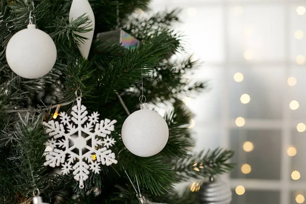 Weihnachtsbaum mit weißen Kugeln in Großaufnahme. Lichter im Hintergrund — Stockfoto