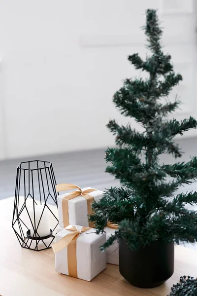 Un petit sapin de Noël et des cadeaux de Noël dans un paquet avec un ruban d'or sur une table en bois — Photo