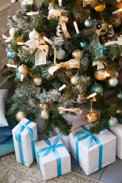 Schöner Weihnachtsbaum mit goldenen Kugeln. Geschenke unter dem mit blauem Band und Schleife geschmückten Weihnachtsbaum — Stockfoto