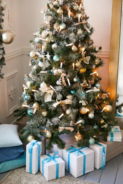 Luxuriöser Weihnachtsbaum in einem Wohnhaus, geschmückt mit vielen Spielzeugen und Kugeln. Geschenke unter dem Baum. — Stockfoto